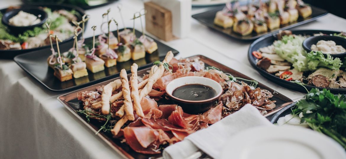Smoked meat,sauce,prosciutto, salad appetizers on table at wedding or christmas feast. Luxury catering concept. Delicious italian food table at wedding reception.
